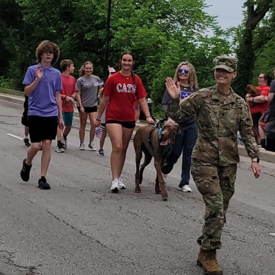 A group of students and a dog walking in a parade.
